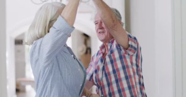 Happy caucasian senior couple having fun dancing together at home, slow motion. Friendship, togetherness and senior lifestyle.