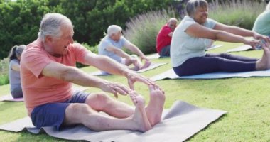 Çeşitli erkek ve kadın yaşlılar bahçede egzersiz yapıyor, ayak parmaklarına dokunuyor, ağır çekimde. Sağlıklı, aktif yaşlı yaşam tarzı.