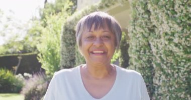 Portrait of happy senior biracial woman smiling and laughing in garden, in slow motion. Healthy, active senior lifestyle.