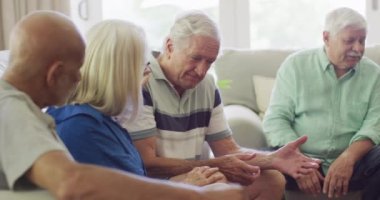 Diverse senior male and female friends consoling sad caucasian man in living room, slow motion. Friendship, support and senior lifestyle.