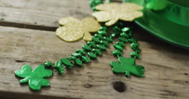 Shamrocks and green hat with copy space on wooden table. Irish tradition and st patrick's day celebration concept digitally generated video.