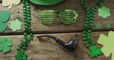 Shamrocks and glasses with pipe with copy space on wooden table. Irish tradition and st patrick's day celebration concept digitally generated video.