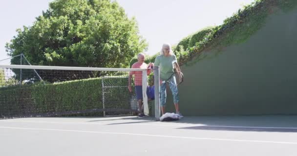 Sonriente Pareja Ancianos Caucásicos Llegando Jugar Tenis Soleada Pista Tenis — Vídeos de Stock