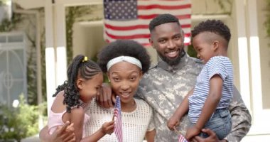 Ailesini kucaklayan mutlu Afro-Amerikan erkek askerinin portresi, ağır çekimde. Yurtseverlik kavramında kaliteli zaman geçirmek.