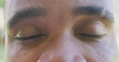 Afro-Amerikan mutlu bir adamın portresi kameraya bakıyor ve gülümsüyor, ağır çekimde. Kaliteli zaman geçirme, ev hayatı 