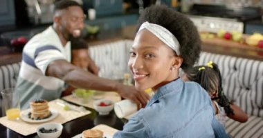 Afrika kökenli mutlu bir Amerikan ailesinin portresi ağır çekimde kahvaltı yapıyor. Ev kavramında kaliteli zaman geçirmek.