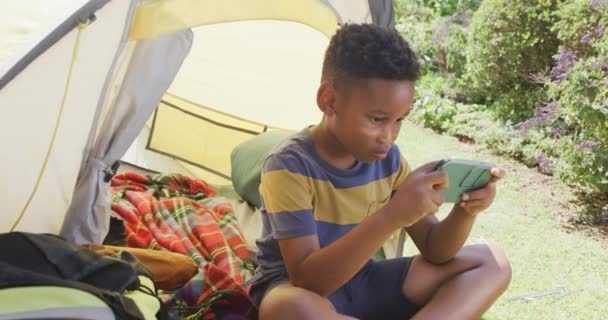 幸せなアフリカ系アメリカ人の少年は テントの中で スローモーションでスマートフォンを使用しています 質の高い時間 家庭生活 子供時代の概念を過ごす — ストック動画
