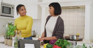 Melez kız kardeşler mutfakta ağır çekimde yemek pişiriyor. Kaliteli zaman, yaşam tarzı, aile hayatı, aile ve kardeş kavramı.