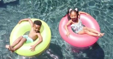 Bilardoda şişme bebekleri olan mutlu Afro-Amerikan kardeşler, yavaş çekimde. Evde ve yaz konseptinde kaliteli zaman geçirmek.