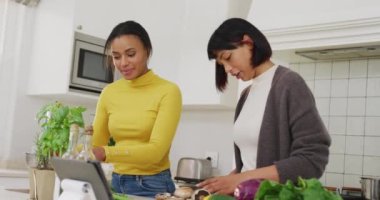 Melez kız kardeşler mutfakta ağır çekimde yemek pişiriyor. Kaliteli zaman, yaşam tarzı, aile hayatı, aile ve kardeş kavramı.