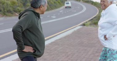Dağlardaki yolda dinlenen son sınıf melez çift. Yürüyüş, sağlıklı yaşam tarzı ve emeklilik kavramı.