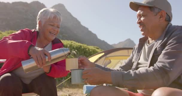 Happy Senior Biracial Couple Sitting Tent Mountains Drinking Coffee Slow — Stock Video