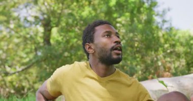 Afro-Amerikalı mutlu bir adam parkta doğayı seyrediyor ve dinleniyor, ağır çekimde. Doğa, yürüyüş ve park konsepti.