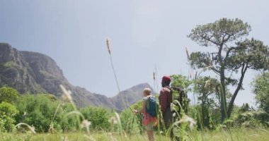 Sırt çantalarıyla yürüyüş yapan ve dağlarda yürüyüş yapan farklı çiftler, yavaş çekim. Doğa, yürüyüş ve manzara konsepti.