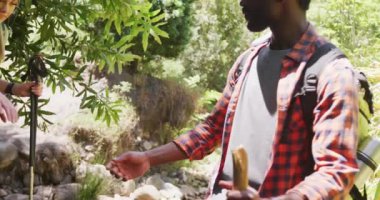 Sırt çantalarıyla parkta yürüyüş yapan mutlu çift, ağır çekimde. Doğa, yürüyüş ve park konsepti.