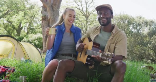 Feliz Casal Diversificado Acampar Beber Chá Tocar Guitarra Parque Câmera — Vídeo de Stock