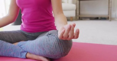 Asyalı bir kadının yatak odasında yoga ve meditasyon yaparken, ağır çekimde. Kaliteli zaman, yaşam tarzı ve ev hayatı kavramı harcamak.