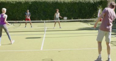 Tenis kortunda oynayan çeşitli arkadaş grupları mutlu olsun. Ev kavramında arkadaşlık ve kaliteli zaman geçirme.