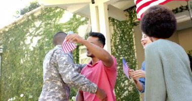 Arkadaşlarını Amerikan bayrağıyla kucaklayan mutlu erkek asker. Yurtseverlik, dostluk ve ev kavramında kaliteli zaman geçirme.