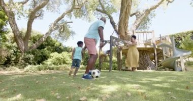 Torunları bahçede yavaş çekimde futbol oynayan mutlu Afro-Amerikan büyükbabaları. Ev kavramında kaliteli zaman geçirmek.