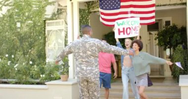 Arkadaşlarını Amerikan bayrağıyla kucaklayan mutlu erkek asker. Yurtseverlik, dostluk ve ev kavramında kaliteli zaman geçirme.