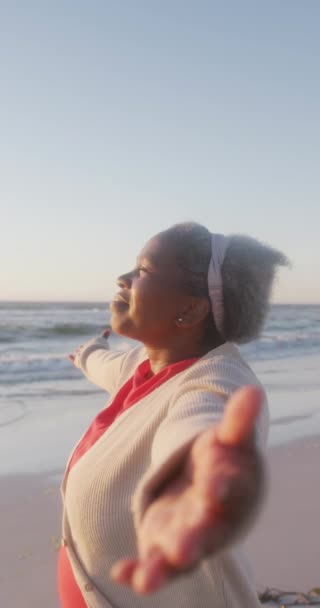 影片中快乐的老年非洲裔美国妇女在海滩张开双臂 动作缓慢 花费高质量的时间 生活方式 退休和度假概念 — 图库视频影像