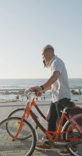 Vídeo Vertical Casal Biracial Feliz Andando Com Bicicletas Passeio Marítimo — Vídeo de Stock