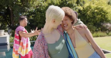 Yazın kucaklaşan ve havluları tutan mutlu arkadaş grubunun portresi. Ev kavramında arkadaşlık ve kaliteli zaman geçirme.