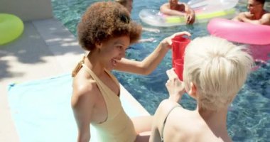 Havuz partisinde şişme şişme ve içki içen mutlu arkadaş portresi. Ev kavramında arkadaşlık ve kaliteli zaman geçirme.