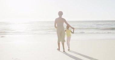 Mutlu Afro-Amerikan anne ve kızları kumsalda ağır çekimde yürüyor. Kaliteli zaman, yaşam tarzı, aile ve tatil konsepti.