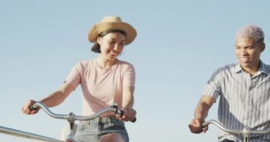 Gezinti güvertesinde ağır çekimde bisiklet süren mutlu çift. Romantizm, eğlence ve tatil kavramı.