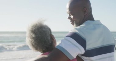 Mutlu Afrika kökenli Amerikalı çiftler kumsalda kucaklaşıyorlar, ağır çekimde. Kaliteli zaman geçirmek, yaşam tarzı, emeklilik ve tatil kavramı.