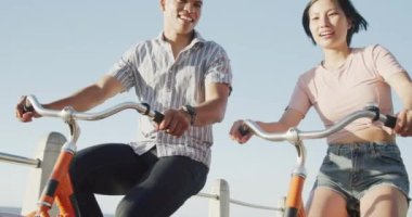 Gezinti güvertesinde ağır çekimde bisiklet süren mutlu çift. Romantizm, eğlence ve tatil kavramı.