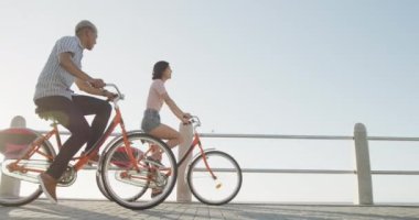 Gezinti güvertesinde ağır çekimde bisiklet süren mutlu çift. Romantizm, eğlence ve tatil kavramı.