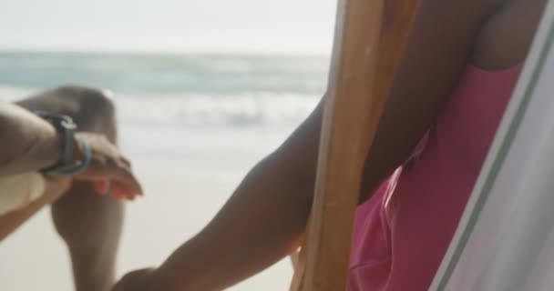 Ένα Ζευγάρι Αφροαμερικανών Κάθεται Ξαπλώστρες Κρατώντας Χέρια Στην Παραλία Αργή — Αρχείο Βίντεο