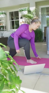 Kafkasyalı mutlu bir kadının ağır çekimde yoga yaptığı dikey bir video. Evde kaliteli zaman geçirmek, vücuda uyum sağlama kavramı.