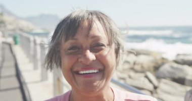 Deniz kenarında gezinen mutlu yaşlı Afrikalı Amerikalı kadın portresi, yavaş çekim. Kaliteli zaman, yaşam tarzı, tatil ve emeklilik.