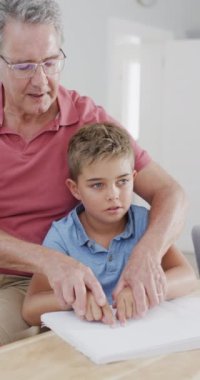 Kafkas baba ve oğlunun masada oturup körler alfabesi ağır çekimde okuduğu dikey bir video. Kaliteli zaman, ev hayatı, körlük, engellilik, aile ve çocukluk kavramı.