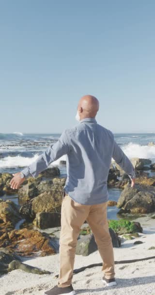 ビーチで腕を広げアフリカ系アメリカ人男性の垂直ビデオ スローモーション 質の高い時間 ライフスタイル 退職の概念を過ごす — ストック動画