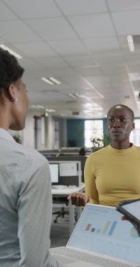 Mutlu Afro-Amerikan iş adamlarının işleri ağır çekimde tartıştıkları dikey bir video. Küresel iş, finans ve ofis kavramı.