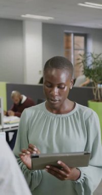 Afro-Amerikan iş adamlarının tableti yavaş çekimde kullandıklarını gösteren dikey bir video. Küresel iş, finans ve ofis kavramı.
