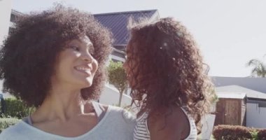 Mutlu Afro-Amerikan anne ve kızı bahçede sarılıp öpüşüyor, ağır çekimde. Evde, evde ve ailede kaliteli zaman geçirmek.
