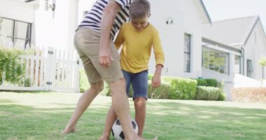 Kafkasyalı mutlu büyükbaba ve torun bahçede futbol oynuyor, ağır çekimde. Kaliteli zaman geçirme, aile hayatı, aile ve çocukluk.