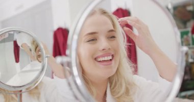 Kafkasyalı mutlu kadın aynanın önünde saçına yavaşça dokunuyor. Yaşam tarzı, evde kaliteli zaman geçirme ve vücut kapsamı.