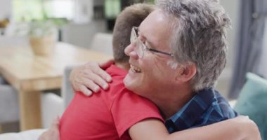 Kafkasyalı büyükbaba ve torun kanepede oturup kucaklaşıyorlar, ağır çekimde. Kaliteli zaman geçirme, aile hayatı, aile ve çocukluk.