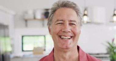 Kameraya bakıp gülümseyen, ağır çekimde mutlu bir beyaz adamın portresi. Kaliteli zaman ve ev hayatı harcamak.