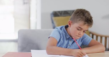 Masada oturup ödev yapan, fotokopi çeken, ağır çekimde mutlu beyaz çocuk. Kaliteli zaman geçirme, ev hayatı ve çocukluk.