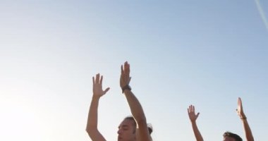 Yoga yapan ve deniz kenarında meditasyon yapan mutlu eşcinsel çift, yavaş çekim. Kaliteli zaman, yaşam tarzı, yaz ve tatil.