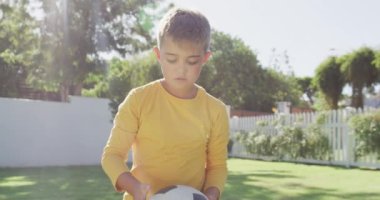Bahçede futbol oynayan mutlu beyaz çocuğun portresi, ağır çekimde. Kaliteli zaman geçirme, ev hayatı ve çocukluk.