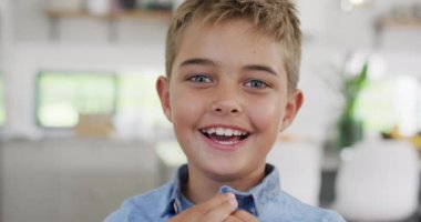 Kameraya bakıp gülümseyen, ağır çekimde mutlu beyaz çocuğun portresi. Kaliteli zaman geçirme, ev hayatı ve çocukluk.